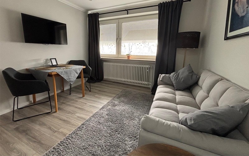 Apartment neu renoviert, Wohnzimmer mit Couch und Fernseher sowie Tageslicht
